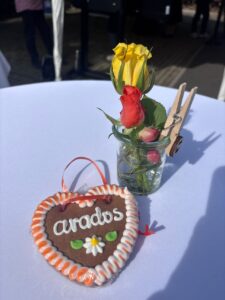 Lebkuchenherz mit arados-Schriftzug und Blumendeko auf einem Stehtisch bei der arados Wiesn 2026